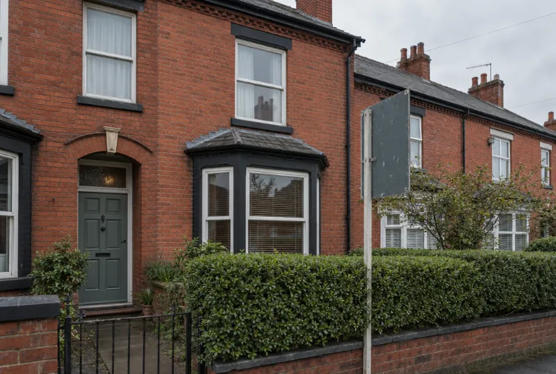 Red-brick terraced house with a sale board in the front garden